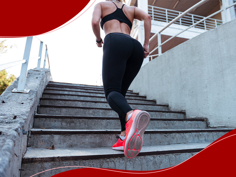 Mulher subindo a escada correndo, de legging e top preto, fazendo exercícios aeróbicos para aumentar os glúteos rapidamente.