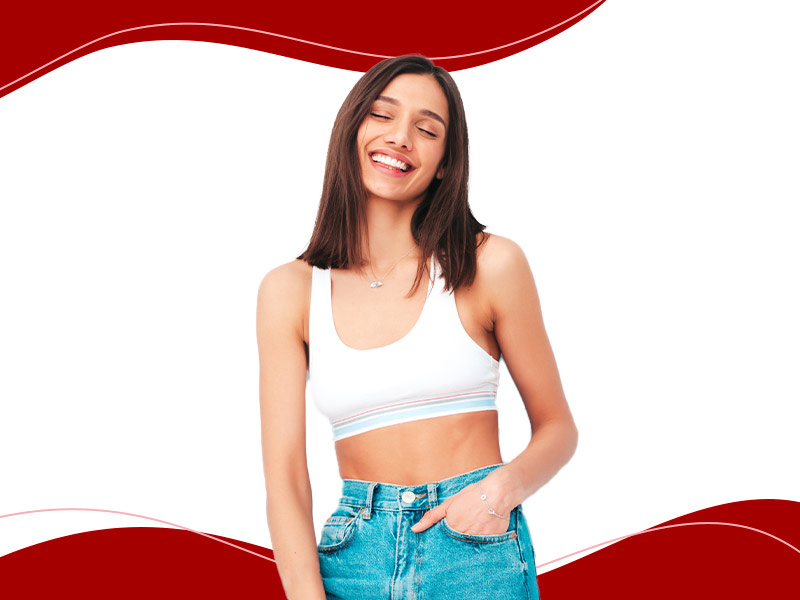 Mulher de top branco e calça jeans sorrindo feliz depois de feito a abdominoplastia com lipo por um preço incrível