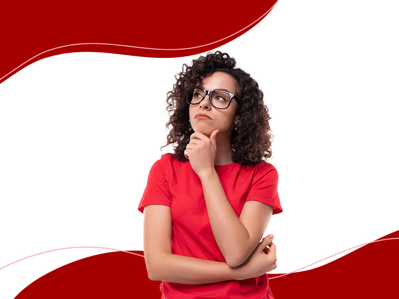 Mulher de camiseta vermelha com cara de pensativa, com a mão no queixo olhando para cima, pensando se o procedimento vale a pena