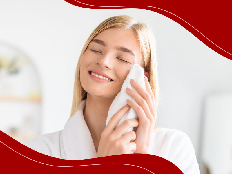 Mulher sorrindo enquanto passa uma toalha branca no rosto